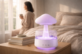 Lura Rain Cloud Diffuser with a purple LED glow on a wooden nightstand, featuring a person relaxing by a window in a cozy, minimalist bedroom.